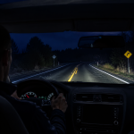 Car headlights illuminating a dark winding road at night for better night driving visibility