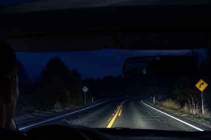 Car headlights illuminating a dark winding road at night for better night driving visibility