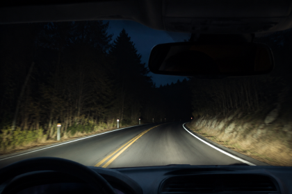 Driver’s view of a car on a dark winding road at night, showing night driving assistance conditions