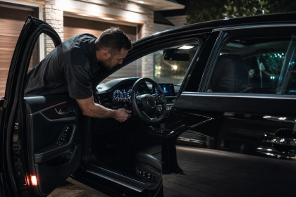 Man inspecting the dashboard of a black luxury car at night during car night vision installation