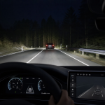Night driving assistance system active on a forest road viewed from inside a car
