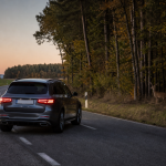 SUV driving on a scenic forest road at sunset in autumn