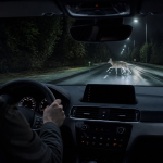 Thermal night vision camera display in a car showing heat signatures on a dark road